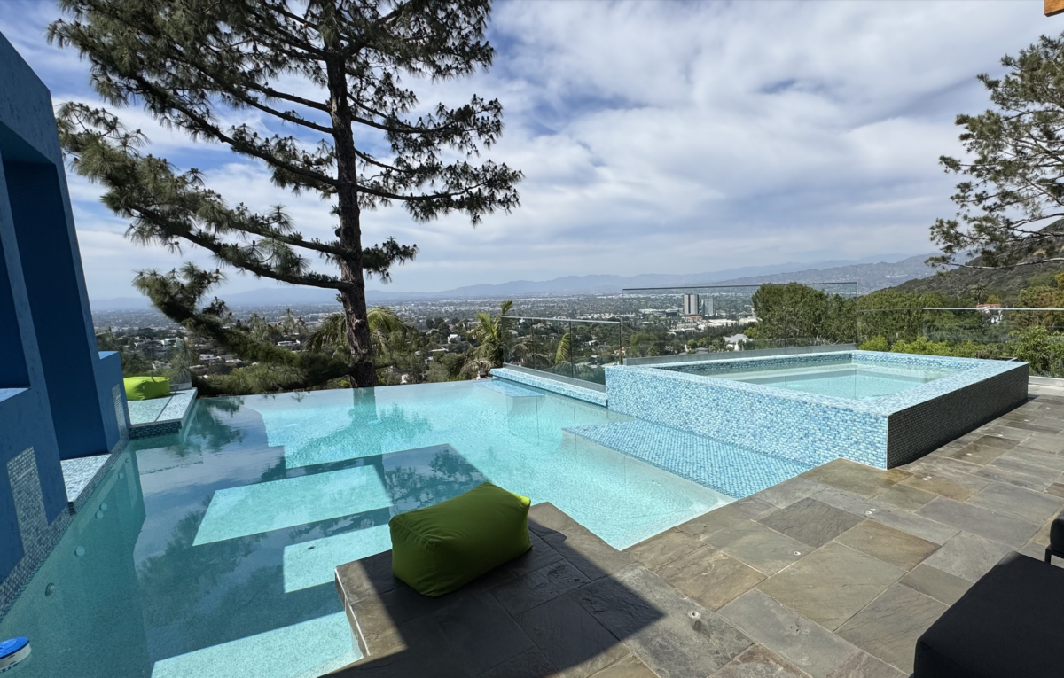 Modern infinity pool and spa with glass railing and hillside city view in Los Angeles