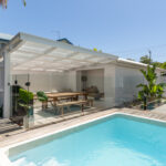 Small rectangular plunge pool beside a covered outdoor dining area and timber deck.