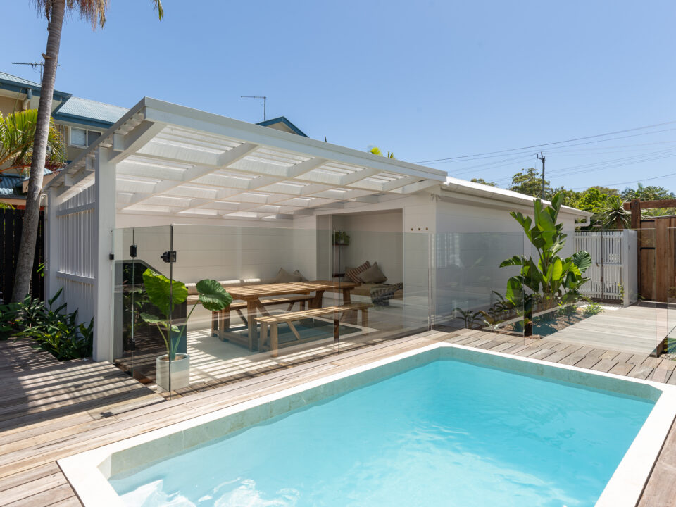 Small rectangular plunge pool beside a covered outdoor dining area and timber deck.